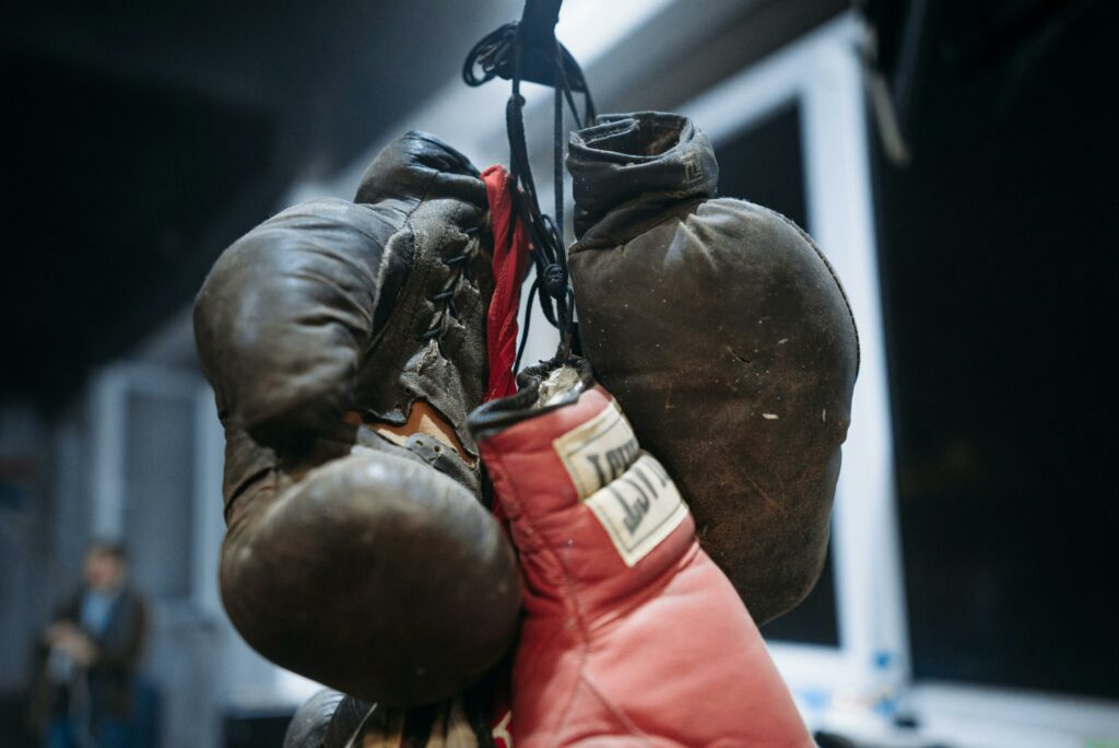 Vintage and modern boxing gloves hanging in a gym setting, capturing the contrast between old and new.